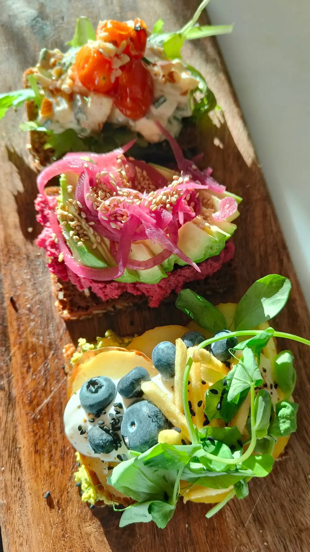 Colourful plant-based open sandwiches on a wooden board at The Break Café